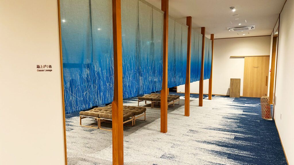 「界 秋保の湯上がり処｜青い暖簾とリラックスチェアが並ぶ落ち着いた休憩スペース」
