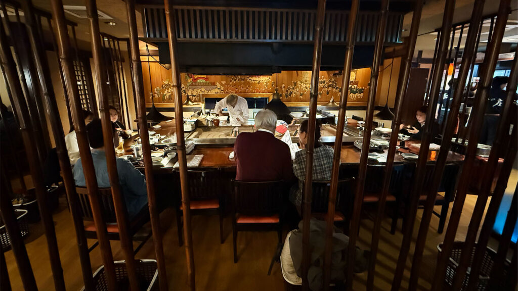 蔵の庄 総本店の囲炉裏カウンター席の様子。落ち着いた和の雰囲気でスタッフが調理する様子が見える店内風景。